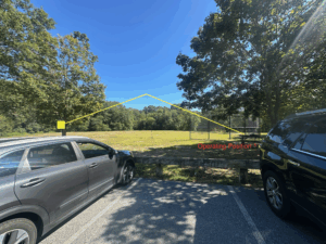 Photo depicts two cars parked next to a baseball field. Yellow lines indicate the invisible wire antenna and orange text highlights the operating position.